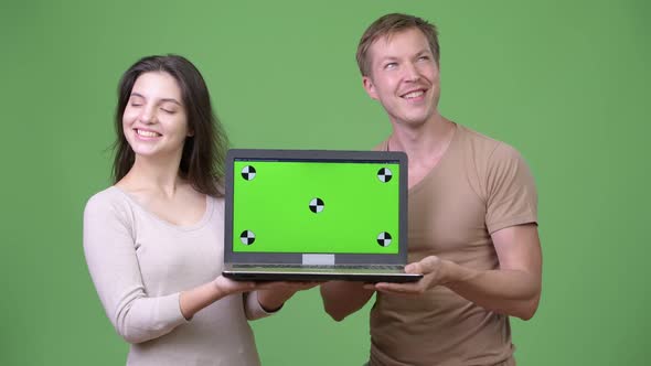 Young Happy Couple Showing Laptop and Thinking Together