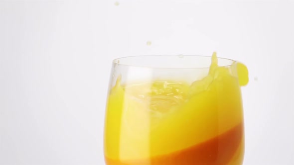 Slice of Orange Falling into a Glass of Orange Juice