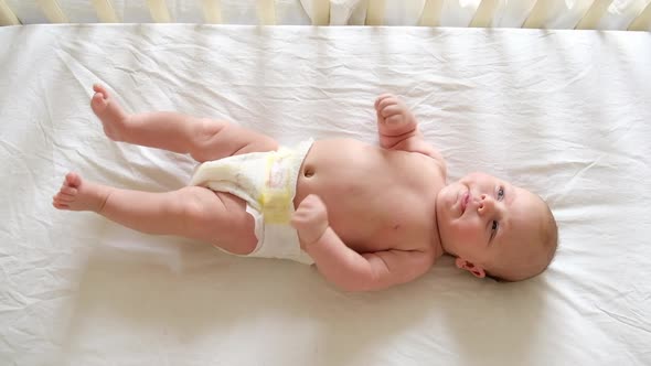 Cute Newborn Baby Lying on the Back in Child Crib