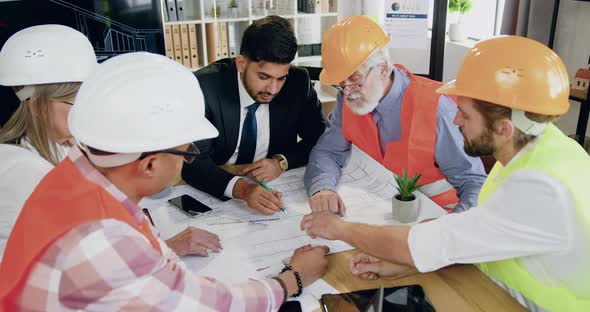 Male and Female Team of Engineers with Bearded Head Engineer Holding a Meeting About Future Building