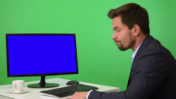A Young Businessman Sits in Front of a Computer and Shakes His Head at the Camera - Green Screen