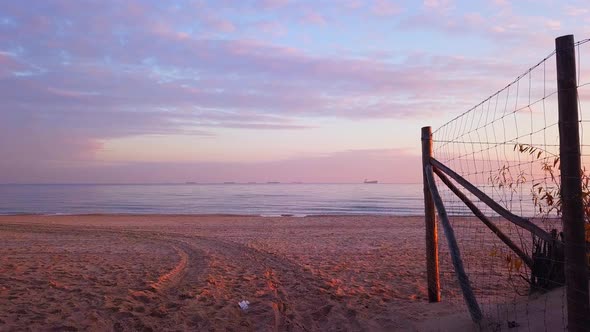 Walking out on a beach during sunrise.  Orange and purple colors. Empty beach. Walking straight forw