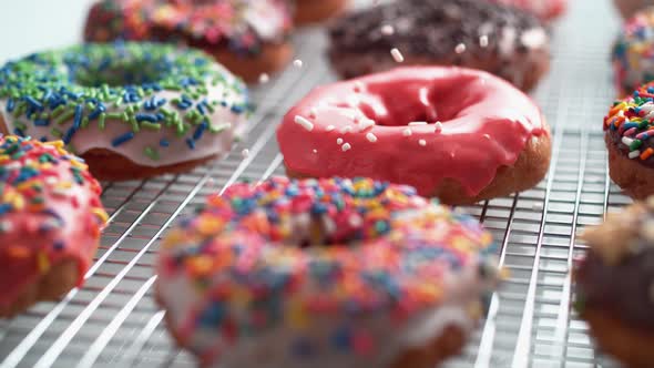 Sprinkling candy chocolate on frosted doughnut. Slow Motion.