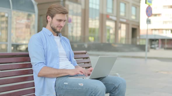 Man with Laptop Showing Thumbs Up Sign While Sitting Outdoor on Bench