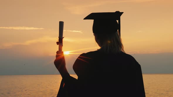 A Woman with a Bachelor's Degree in a Robe and a Graduate Cap at Sunset