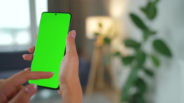 Woman at Home Using Smartphone with Green Mockup Screen in Vertical Mode