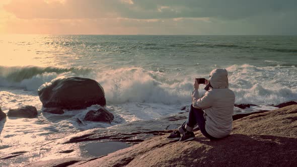 Young Woman Taking Picture of Rocky Coast of Atlantic Ocean on Smartphone