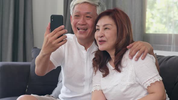 Asian senior couple video call using mobile phone video call talking with family.