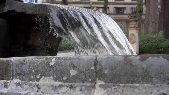 Close-up fountain cascade water stream with concrete walls in the old city park