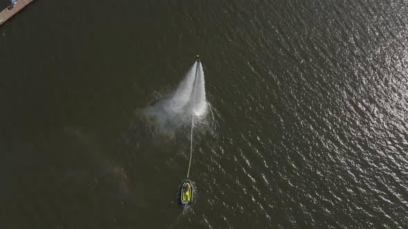 A Man Flies Over the River on a Flyboard and Dives Into the Water