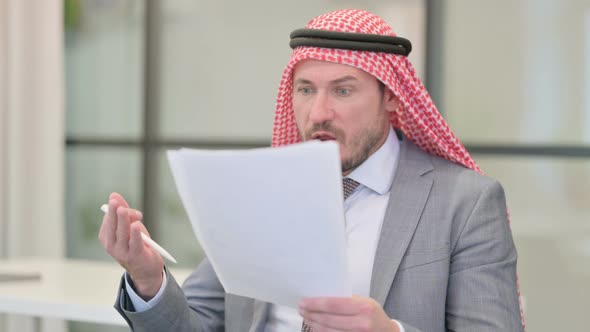 Middle Aged Arab Businessman Reacting to Loss while Reading Documents in Office