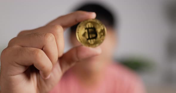 Close up of Asian man holding bitcoin. Blurred man show cryptocurrency