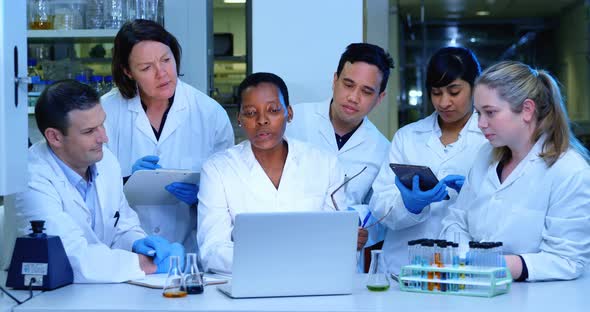 Team of scientist discussing over a laptop 4k