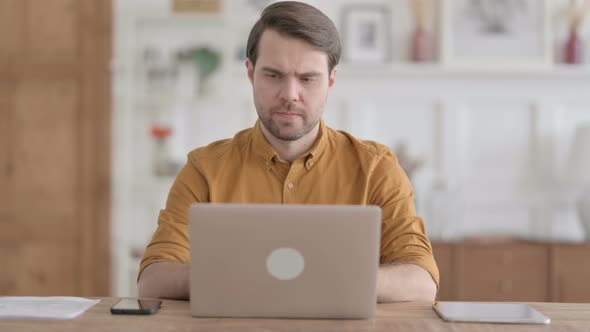 Young Man Working on Laptop in Office