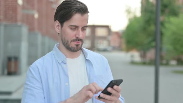 Man Celebrating on Smartphone While Standing Outdoor