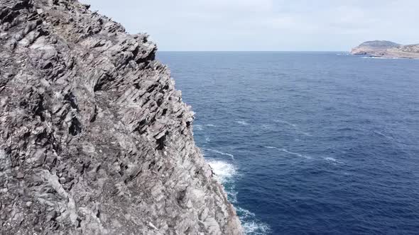 Drone flies incredibly close to sharp rocks overlooking the sea (Sardinia)