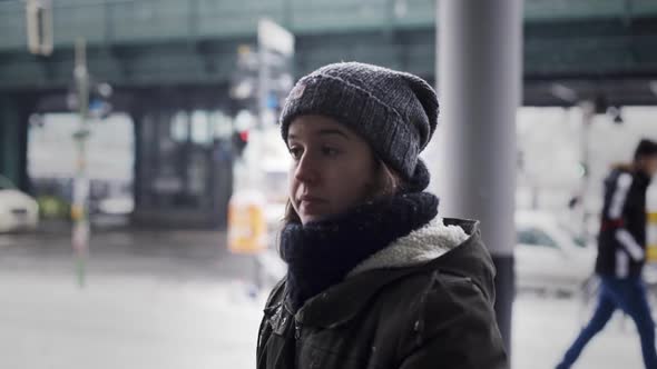 Young Caucasian woman wearing winter hat, scarf and jacket, staring into oblivion and in daze waitin