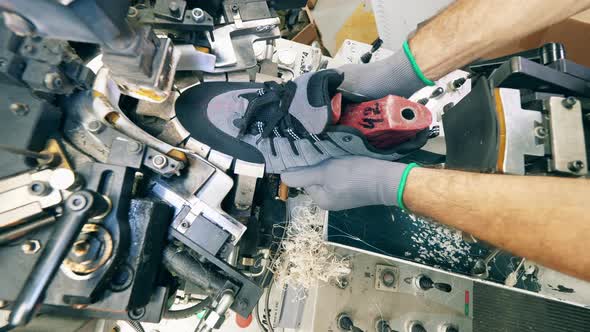 Footwear Factory Worker Making Shoes. Lasting Machine Is Being Used To Shape a New Boot