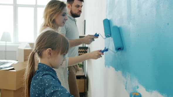 Young Couple with Child Remodelling House Painting Wall and Dancing Enjoying Music