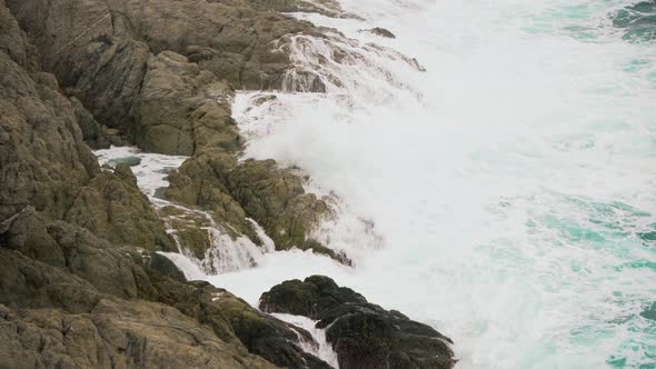 Waves crashing against rocks in the ocean, sea foam splashing