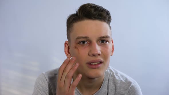 Unhappy Teenager With Wound on Face Touching It and Looking to Camera, Fight