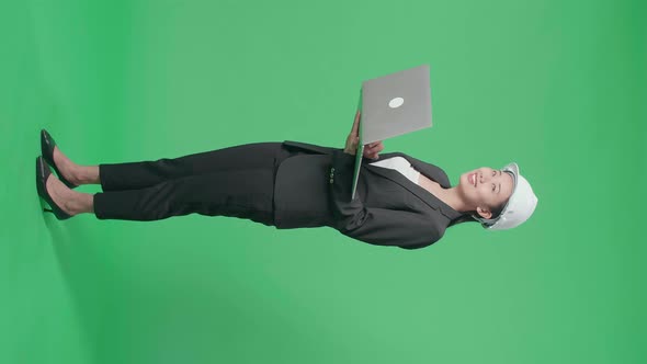 Side View Of Asian Female Engineer Looking Around While Using Laptop In The Green Screen Studio