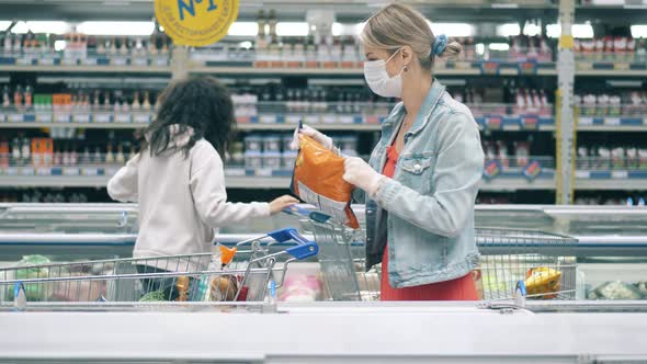 A Lady in a Face Mask is Buying Frozen Food in the Supermarket