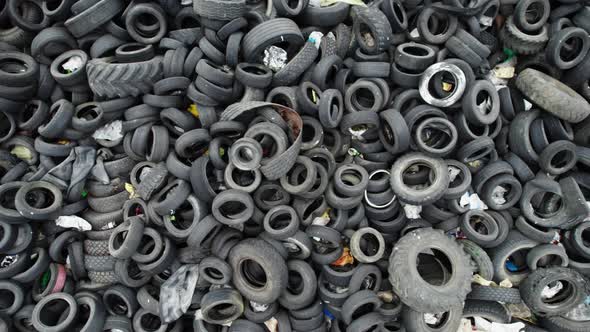 Aerial top view of a junkyard of old car tires. Slow camera motion over a tire dump.