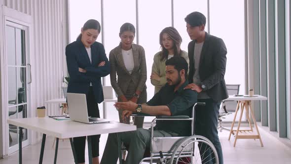 A disabled company employee is explaining a computer program to a group of colleagues.