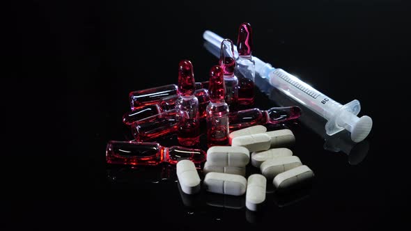 White pills, medicine ampoules with red vaccine, drugs or narcotics and syringe
