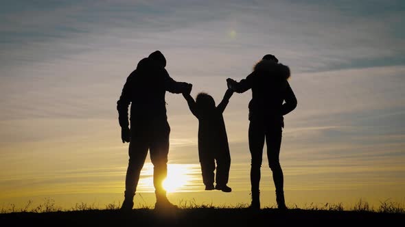 Happy Young Family Together with Their Little Child at Sunset