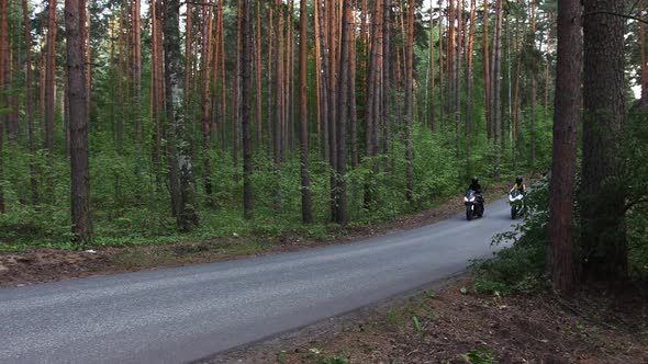 Motorbikes in the Forest  Two Women Riding Black Motorcycles on the Empty Narrow Road in the Woods