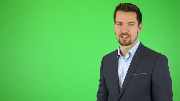 A Young Handsome Businessman Talks To the Camera and Taps at Three Places in the Air in Front of Him