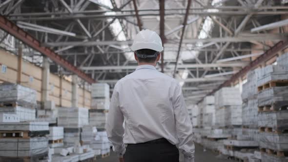 Follow footage of employees male warehouse worker engineer in hard hat working.