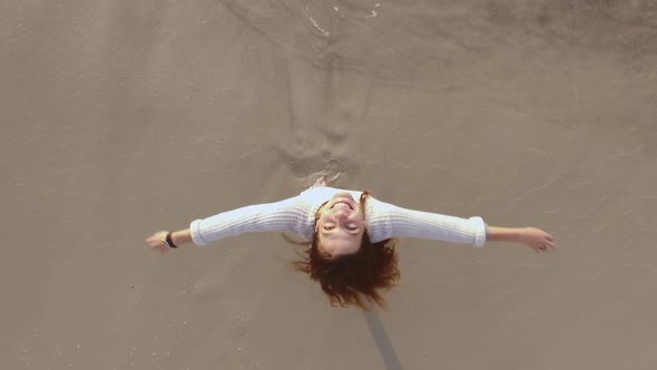 Beautiful Young Woman Happily Spinning with Stretched Out Arms Looking Up Touching Her Long Hair