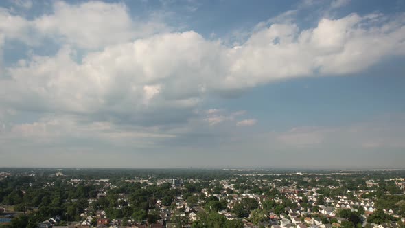 An aerial time lapse over a quiet suburban neighborhood on a sunny day with blue skies with white cl