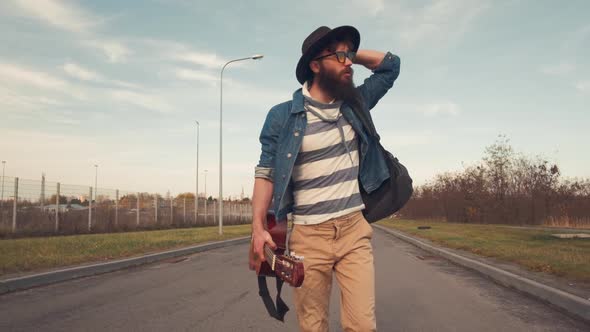 Portrait Bearded Male Musician with Dark Warm Eyes Walking in the Park on a Sunny Day with a Guitar