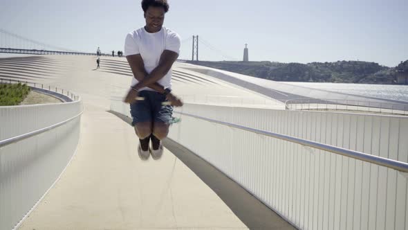 Smiling African American Sportsman Skipping Rope on Bridge