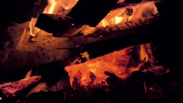 Orange flames glow as a bonfire burns on a sandy beach. Slow motion view.