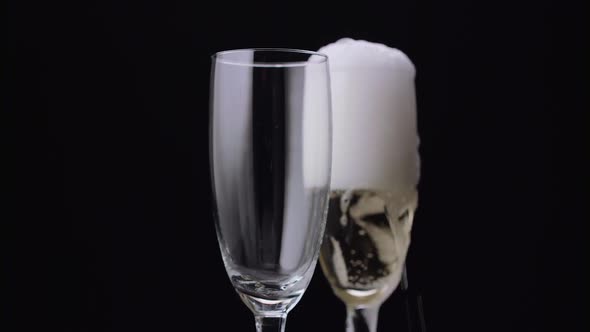 Waiter Pours the Champagne in Two Glasses. Black Background. Close Up