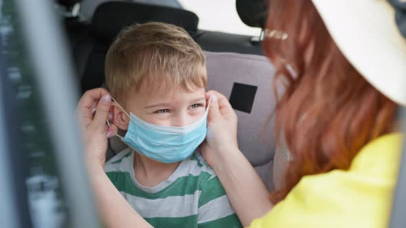 Loving Mother Puts Protective Medical Mask on Her Son in Car Seat To Protect Against Virus and