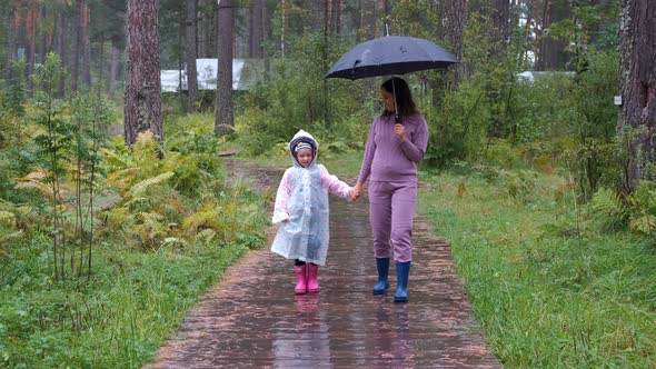 Little Girl with Mom Walking in Autumn Rainy Day