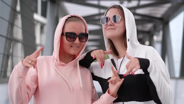 Two Girls are Dancing to Rap They are Wearing Sweaters with Hoods on Their Heads