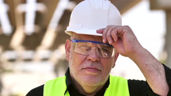 Close Up Portrait of Mature Master Builder in White Safety Hard Hat Looking at Camera Standing at