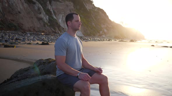 A strong young man in silhouette sitting in a meditation pose to release stress and train mindfulnes