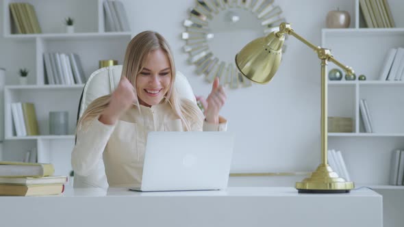 Happy woman receiving good news at the desk in home office