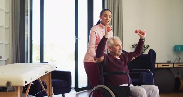 Video of happy biracial female physiotherapist exercising with caucasian senior man