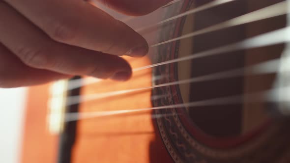 Closeup Fingers of Musician Man Playing on Strings of an Acoustic Guitar Performing Music