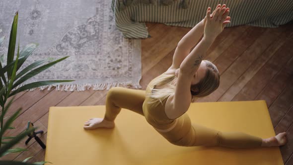 Slim Blonde Young Woman Does Yoga on Mat Lying on Floor