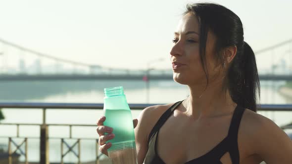 Shot of a Beautiful Woman Enjoying Drinking Water Outdoors